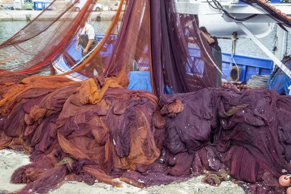 Montón de redes de pesca y barco de pesca amarrado —  Fotos de Stock