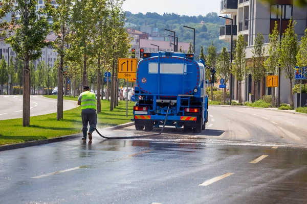 일꾼들은 거리를 청소하고 콘크리트 트럭이 아스팔트를 소독하다 스톡 사진