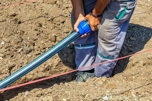 ポリプロピレンパイプの接続は 掘削トレンチ内の水パイプを接続します 労働者は溝に水道管を保持し ポリプロピレンを結合する — ストック写真
