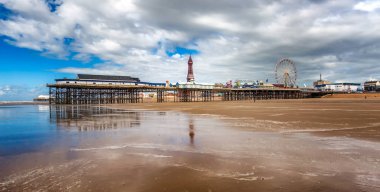 Serene Blackpool beach scene featuring the iconic pier and ferris wheel on a sunny day with reflections on wet sand.Central pier at low tide, reflections of the pier in the water clipart