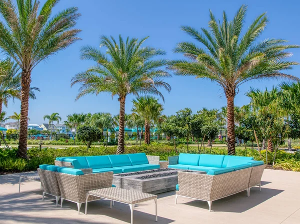 Margaritaville Resort Orlando. Aqua couches under palm trees mark a lounge area for outside seating at hotel.