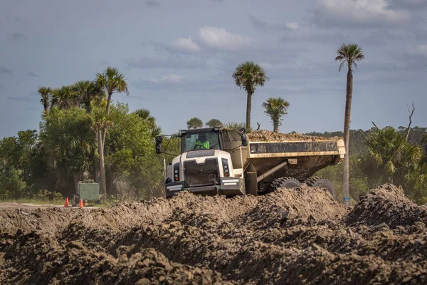 Construction Vehicle - Dump truck with load of dirt in the middle of a swamp.