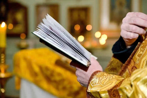 Концепция церковных таинств - крещение, свадьба, Пасха, воскресение. Молитвенник в руках православного священника на фоне церковных свечей крупным планом . — стоковое фото