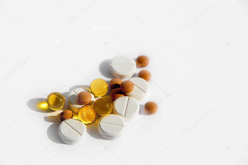 The concept of a healthy lifestyle, treatment of diseases, proper nutrition and medicine. Various pills loose on a light background.