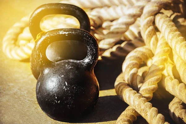 Spor salonu, Fitness, sağlık ve uygun yaşam tarzı sert eğitim kavramı. Güneşten parlama ile ipler bir arka plana karşı katta iki eski çizilmiş dökme demir dambıl. Closeup