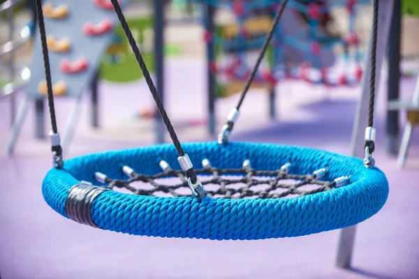 Oyun Alanı'nda mavi yuvarlak salıncak tipi yuva. Çocuklar ve ergenler için spor rekreasyon kavramı, mutlu bir çocukluk.