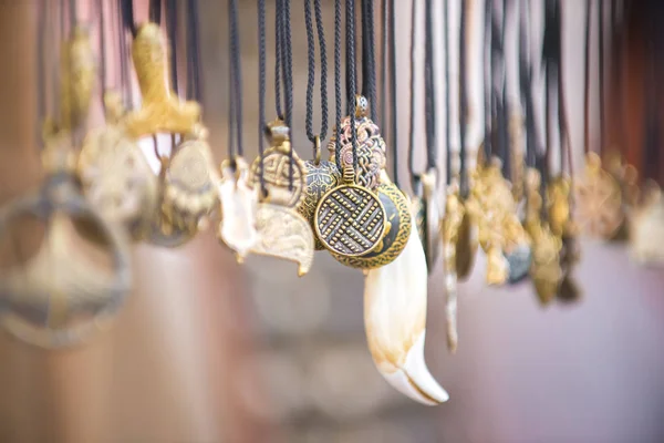 Bijuterii handmade și diverse amulete atârnă pe șireturile de pe stand la târg . — Fotografie, imagine de stoc
