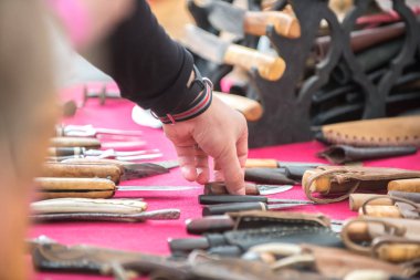 Bir adam fuarda metal bıçak ve ahşap saplı el yapımı bir bıçak seçer..