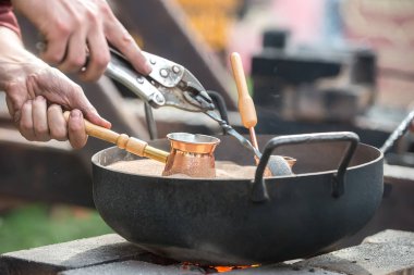 Fuar ustalarında bir tencerece kumda kahve demleme süreci.