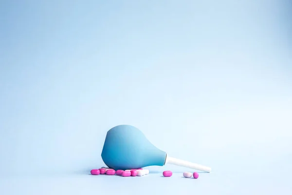 Blue douche mentiras e pílulas são rosa e branco em torno de um fundo azul . — Fotografia de Stock
