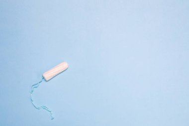 Mavi arka plan üzerinde sıkıştırılmamış tampon beyaz, kadınların samimi hijyen ve sağlık kavramı.