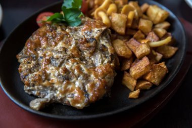 Koyu bir arka plan üzerinde demir tavada mantar ve rustik patates ile Et.