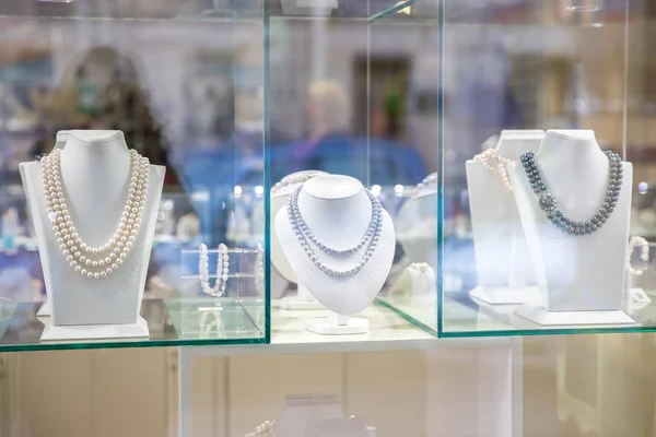Üç manken ve inci bir kolye ile güzel bir pencere.