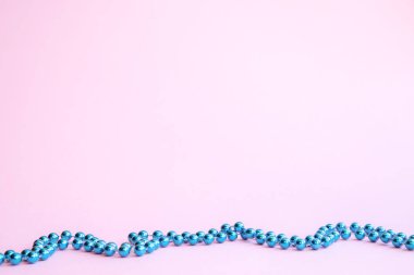 Pembe arka plan üzerinde bir çizgi yapay mavi boncuklar. Festival arka plan, yeni yıl.