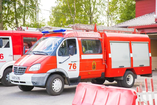 2019, Petrohrad, Rusko. Záchranáři červených aut s žebříkem nahoře s nápisy v oblasti u brány požární stanice, připraveni jít na hovor. — Stock fotografie