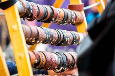 Kabartmalı ve perçinli farklı renklerde güzel deri bilezikler, mevsimlik ustalar fuarında standda asılı.