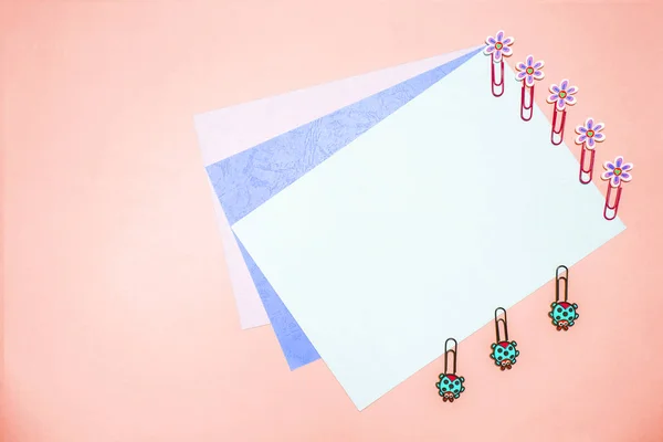 Ofis: pembe copyspace arka plan, karton birkaç yaprak ve papatyalar ve uğur böceği mat renkler şeklinde güzel ataş.