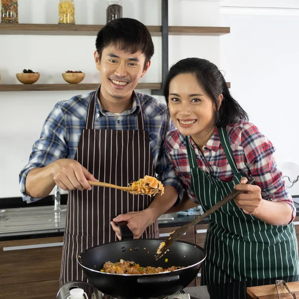 Young Asian couple are happy to cook together, two families are helping each other prepare to cook in the kitchen.