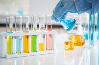 Bilim adamları elinde cam bir tüp tutuyorlar. Bazı maddeleri hazırlamak ve test etmek için, laboratuvarda scientst araştırma