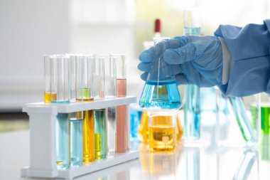 Bilim adamları elinde cam bir tüp tutuyorlar. Bazı maddeleri hazırlamak ve test etmek için, laboratuvarda scientst araştırma