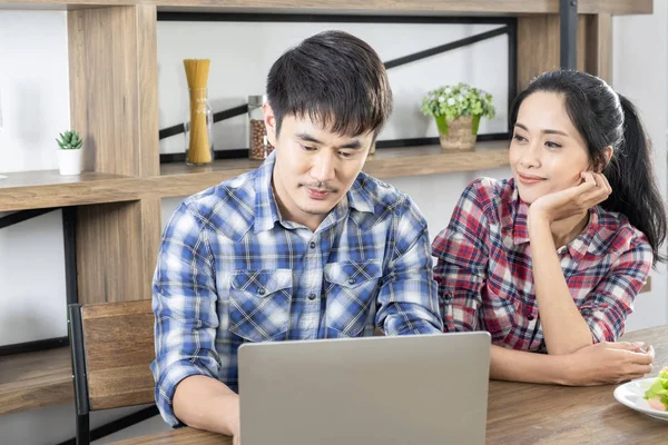 Genç Asya güzel çift online alışveriş için dizüstü bilgisayar izlerken, ya da ev ofis küçük işletmeler için internet kullanımı