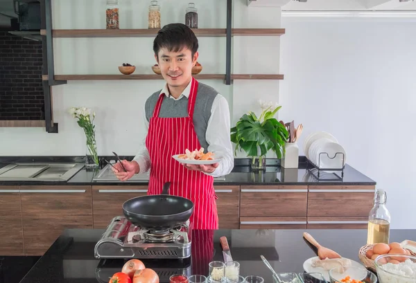 Handsome, Asian young man Smiling happiness. Holding fried sausage on dishes for  food in the kitchen. and people concept, copy space.