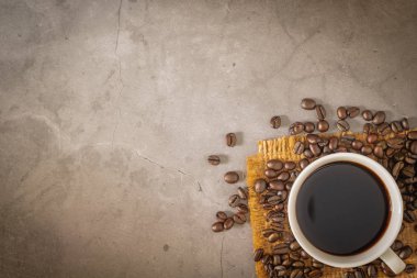 Cup of a black coffee and beans on sack with old cement floor. Top view, copy space clipart