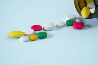 Renkli, çeşitli ilaç hapları şişeden döküldü. birçok hap ve tablet mavi arka plan izole.