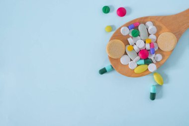 Düz Lay, Renkli Top View, Çeşitli farmasötik ilaç hapları. Kopya alanı ile mavi arka plan üzerinde izole ahşap kaşık birçok hap ve tablet. tıp kavramı .