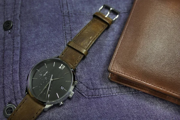 Men's accessories classic and luxury watch brown leather strap with wallet on blue jean shirt. for life stlye, elegant to dress of businessmen or casual stlye.