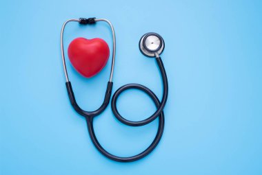 Siyah steteskop, mavi arka planda kontrol için doktorun kırmızı kalbi. Stetoskop ekipmanları ses tanısı koymak için kullanılır. Sağlık ve kardiyoloji konsepti. Kopyalama alanı olan düz.