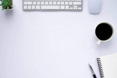 Ofiste beyaz masalı çalışma alanı. Not defteri ve kahveyle klavyenin üst görüntüsü. Modern yaratıcı tasarımcılar için masa. Boş fotokopi alanı olan düz bir yer. İş ve finans kavramı.
