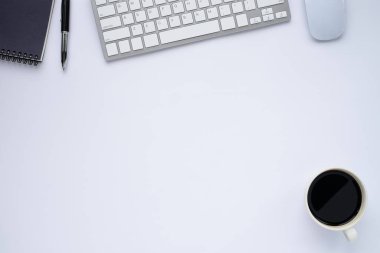 Klavyeli beyaz ofis masası, defter ve kahve fincanı diğer ofis malzemeleriyle dolu. İş ve finans kavramı. Boş kopya alanı ile düz yatıyordu.