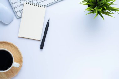 Klavyeli beyaz ofis masası, defter ve kahve fincanı diğer ofis malzemeleriyle dolu. İş ve finans kavramı. Boş kopya alanı ve üst görünümü ile düz uzandı.