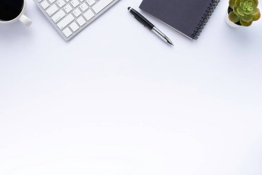 Üzerinde klavye, defter ve kahve fincanı olan beyaz ofis masasının üst görüntüsü diğer ofis malzemeleriyle dolu. İş ve finans kavramı. Boş kopya alanı ile düz yatıyordu.