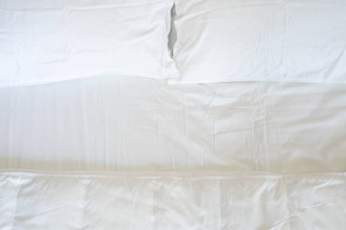 Yatak odasındaki rahat yatakta yorgan ve çarşaflı temiz, yumuşak yastıkların üst görüntüsü..