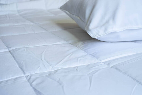 Close-up of clean white soft pillow on the comfortable bed in the bedroom.