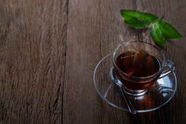 Tahta masa arkasında kaşık ve yeşil çay yaprağı olan sıcak organik çay fincanı. Sabah için sağlıklı bitkisel içecekler insanı ferahlatıyor. kopyalama alanı ile.