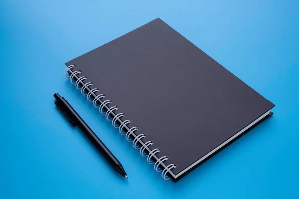 モックアップをデザインするための青の背景に分離ペンと黒スパイラルノートブック 教育事業の概念 — ストック写真