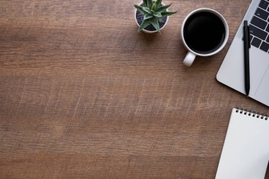 Ahşap ofis masası, dizüstü bilgisayarı, kahve fincanı ve diğer ofis malzemeleri. İş ve finans kavramı. Çalışma yeri, boş kopya alanı olan düz uzanma, Üst görünüm.