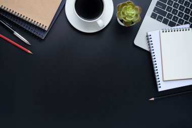 Laptoplu siyah ofis masası, defter ve kahve fincanı diğer ofis malzemeleriyle dolu. İş ve finans kavramı. Çalışma yeri, boş kopya alanı olan düz uzanma, Üst görünüm.