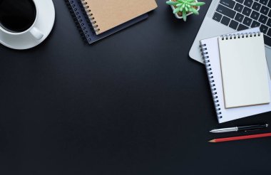 Laptoplu siyah ofis masası, defter ve kahve fincanı diğer ofis malzemeleriyle dolu. İş ve finans kavramı. Çalışma yeri, boş kopya alanı olan düz uzanma, Üst görünüm.