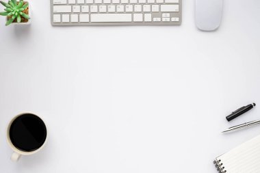 Klavyeli beyaz ofis masası, defter ve kahve fincanı diğer ofis malzemeleriyle dolu. İş ve finans kavramı. Çalışma yeri, boş kopya alanı olan düz uzanma, üst görünüm.