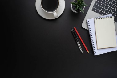Laptoplu siyah ofis masası, defter ve kahve fincanı diğer ofis malzemeleriyle dolu. İş ve finans kavramı. Çalışma yeri, boş kopya alanı olan düz uzanma, Üst görünüm.