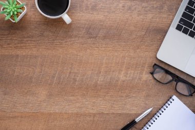 Ahşap ofis masasının üstünde klavye, defter ve diğer ofis malzemeleriyle dolu kahve fincanı var. İş ve finans kavramı. Çalışma yeri, boş kopya alanı olan düz uzanma.