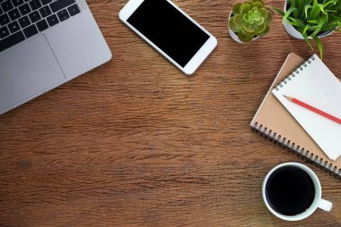 Klavyeli ahşap ofis masası dizüstü bilgisayar, defter ve cep telefonlu kahve fincanı. İş ve finans kavramı. Çalışma yeri, boş kopya alanı olan düz uzanma, üst görünüm.