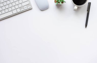 Beyaz ofis masasının üstünde klavye, defter ve kahve fincanı ve diğer ofis malzemeleri. İş ve finans kavramı. Çalışma yeri, boş kopya alanı olan düz uzanma.