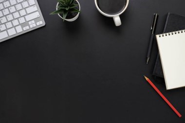 Siyah ofis masasının üstünde klavye, defter ve kahve fincanı ve diğer ofis malzemeleriyle. İş ve finans kavramı. Çalışma yeri, boş kopya alanı olan düz uzanma.