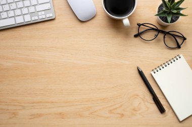 Ahşap ofis masasının üstünde klavye, defter, fare ve diğer ofis malzemeleriyle dolu bir masa. İş ve finans kavramı. Çalışma yeri, boş kopya alanı olan düz uzanma.