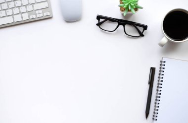 Beyaz ofis masasının üstünde klavye, defter ve kahve fincanı ve diğer ofis malzemeleri. İş ve finans kavramı. Çalışma yeri, boş kopya alanı olan düz uzanma.